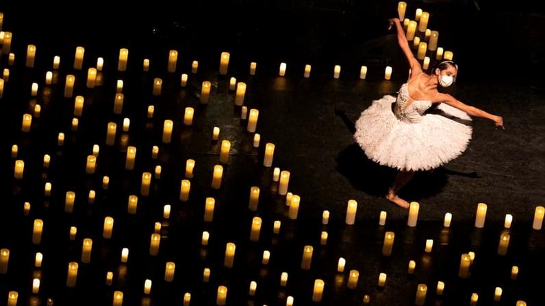 Bailarina dança em palco cheio de velas acesas