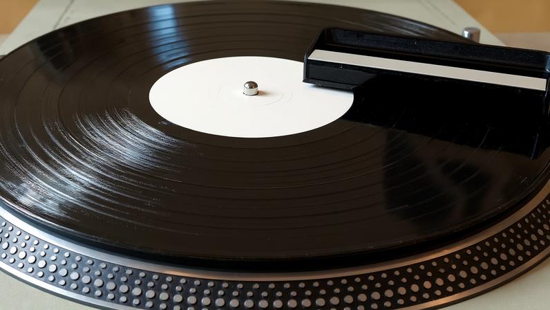 Closeup of vinyl record player with a cleaning brush on top