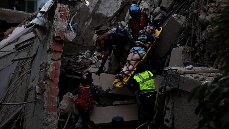 Socorristas carregam mulher ferida em escombros de prédio destruído por terremoto em Caracas, na Venezuela