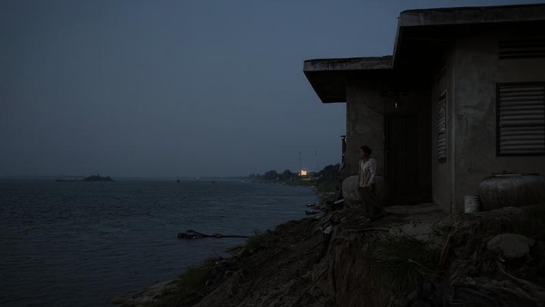 Voi Thy, a resident of Roka Koang, Cambodia, watches the Mekong River where sand mining barges pass by.