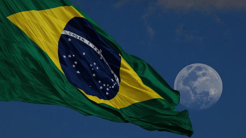 Na foto, bandeira do Brasil no mastro da Praça dos Três Poderes, tendo a lua ao fundo