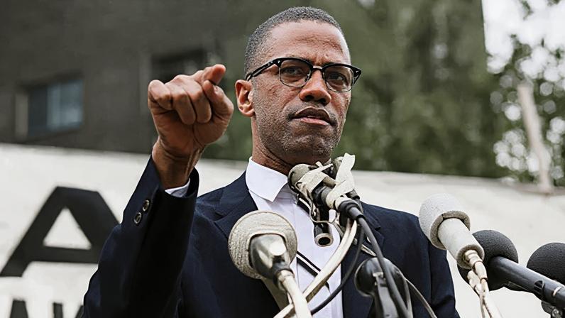 Getty Images A black-and-white photo of Malcolm X speaking at a podium (Credit: Getty Images)