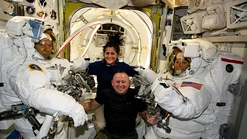 Os astronautas do teste de voo da tripulação da Starliner, da Boeing, Suni Williams e Butch Wilmore (no centro), posam com os engenheiros de voo da Expedição 71 da ISS, Mike Barratt e Tracy C. Dyson, ambos astronautas da Nasa, em seus trajes espaciais a bordo da câmara de descompressão da Estação Espacial Internacional