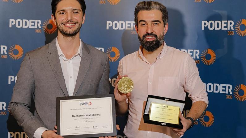 O diretor de Inovação do Poder360, Miguel Rodrigues (esq.), entrega o prêmio ao vencedor do 1º Prêmio Poder de Jornalismo, o editor sênior Guilherme Waltenberg (dir.)