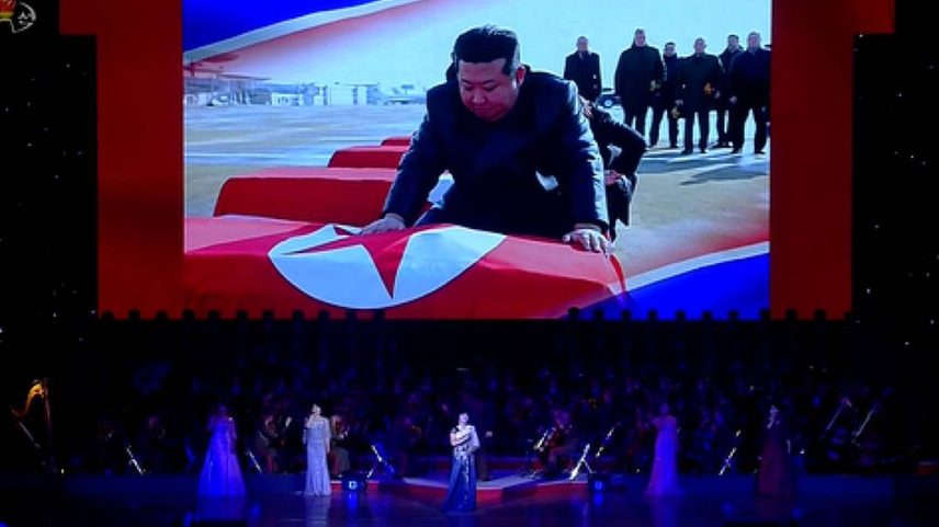 Telão mostra Kim Jong-un colocando a bandeira norte-coreana em caixões de soldados mortos lutando pela Rússia (Foto: KCNA)