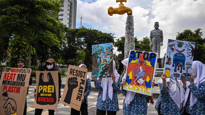 Ativistas protestam contra poluição diante de instalação que mostra uma torneira da qual saem embalagens plásticas em Surabaya, na Indonésia (Foto: Juni Kriswanto/AFP)
