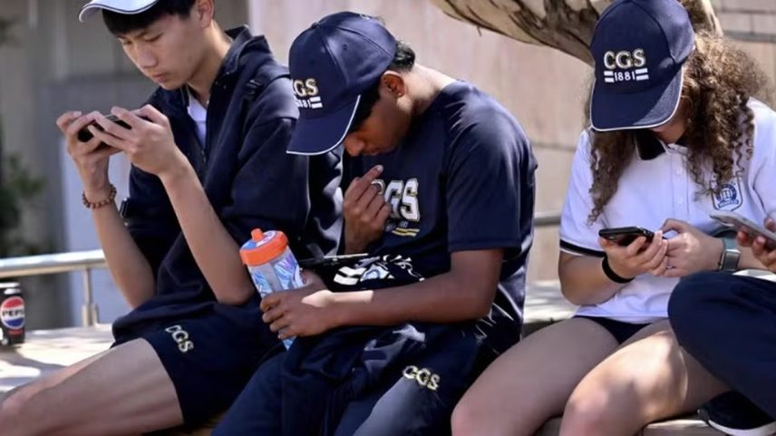 Estudantes olham seus telefones em Melbourne, enquanto a Austrália procura banir jovens menores de 16 anos das mídias sociais (Foto: William West / AFP)