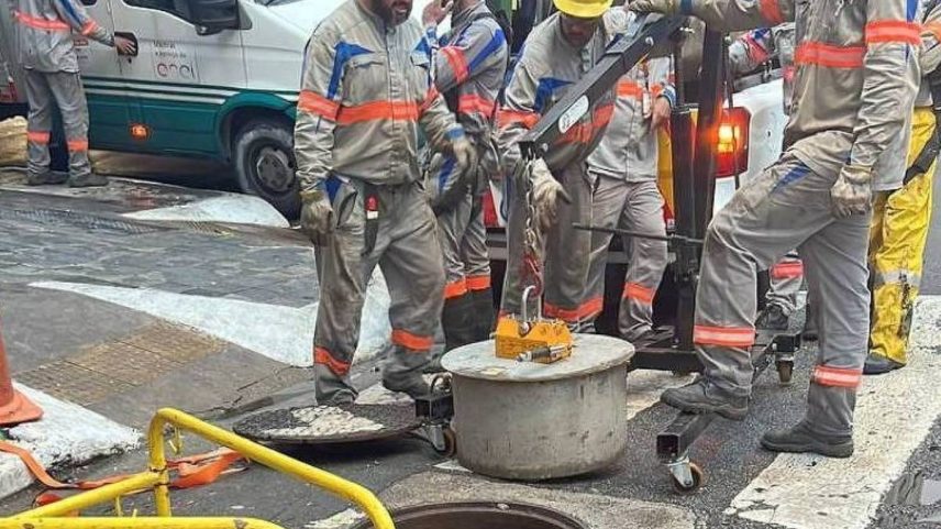 Funcionários da Enel manipulam tampa de concreto de caixa subterrânea de energia com ajuda de guindaste (Foto: Divulgação/Enel)