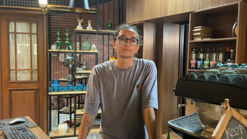 Um homem iraniano em pé atrás de um balcão em uma loja (Foto: Reprodução)