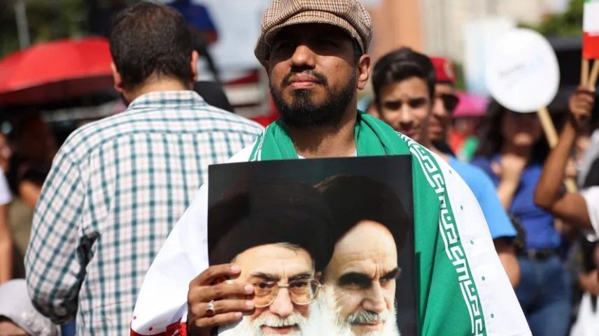 Manifestante segura foto com as imagens do líder supremo do Irã, Ali Khamenei, e do fundador da República Islâmica, aiatolá Ruhollah Khomeini (Foto: Pedro MATTEY / AFP)