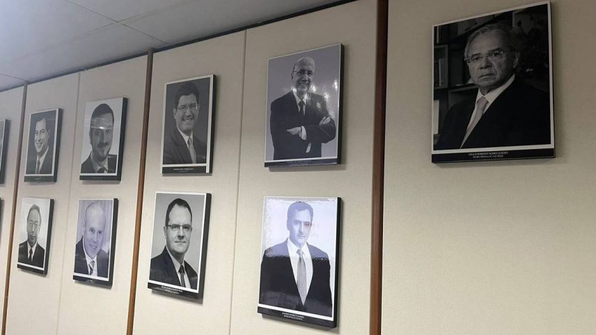 Foto do ex-ministro Paulo Guedes (à dir.) na galeria de ex-titulares da pasta, na sede do ministério, em Brasília (Foto: Idiana Tomazelli/Folhapress)