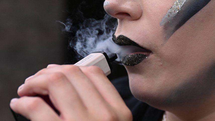 Jovem usa vape em entrada de teatro em Londres, na Inglaterra (Foto: Jaimi Joy - 31.mai.2025/REUTERS)