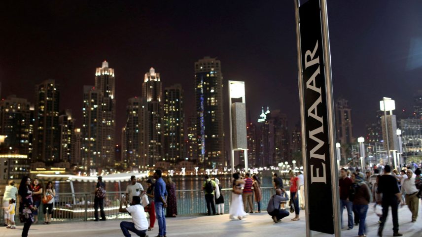 Pessoas tiram fotos perto de uma placa da Emaar em frente ao Dubai Mall - 15/03/2024 (Foto: REUTERS/Ahmed Jadallah)
