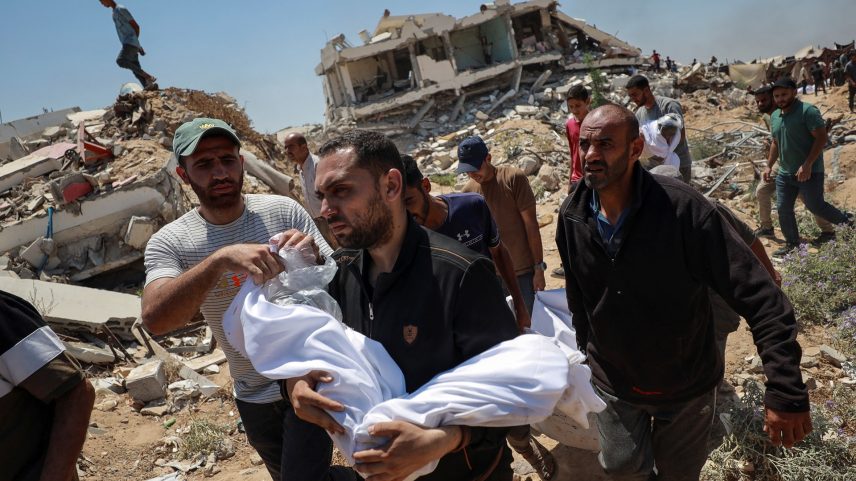 Homem carrega o corpo de uma criança durante o funeral dos palestinos da família Azzam, mortos em um ataque israelense noturno à sua casa, de acordo com médicos, antes de enterrá-los em um terreno devido à falta de espaço nos cemitérios superlotados de Gaza, na Cidade de Gaza, em 15 de julho de 2025. (Foto: REUTERS/Khamis Al-Rifi)