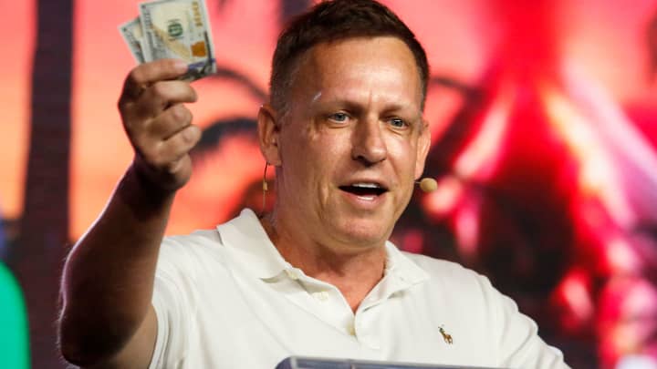 Peter Thiel, cofundador do PayPal, Palantir Technologies e Founders Fund, segura notas de cem dólares enquanto fala durante a Conferência Bitcoin 2022 no Miami Beach Convention Center em 7 de abril de 2022, em Miami, Flórida. (Foto: Marco Bello | Getty Images)