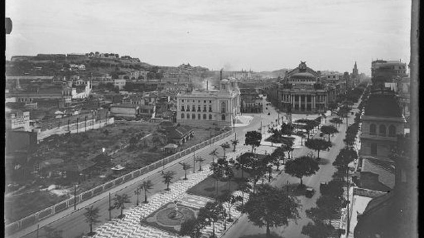 Fotografia mostra a Cinelândia ainda em construção. Em primeiro plano, a Praça Marechal Floriano ao fundo, os prédios do Conselho Municipal do Rio de Janeiro e do Theatro Municipal (Foto: Autoria não identificada/ Acervo IMS)
