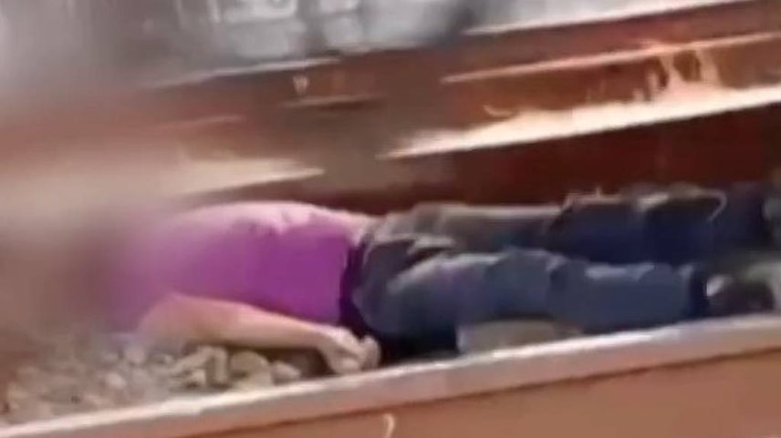 Homem deitado na linha férrea da CPTM, em Itaquaquecetuba, enquanto composição passa em cima dele (Foto: Reprodução/TV Diário)