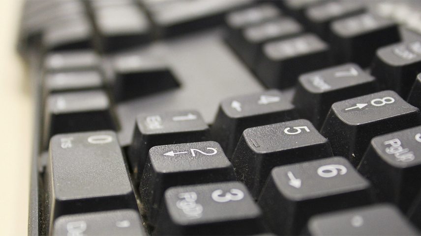 Teclado de computador em close, com as teclas direcionais e de números, na cor preta, em primeiro plano (Foto: USP Imagens)