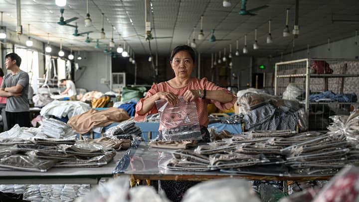 Um funcionário embala roupas para a empresa de e-commerce online chinesa Temu em uma fábrica de roupas em Guangzhou, na província de Guangdong, no sul da China, em 16 de abril de 2025. (Foto: Jade Gao | Afp | Getty Images)