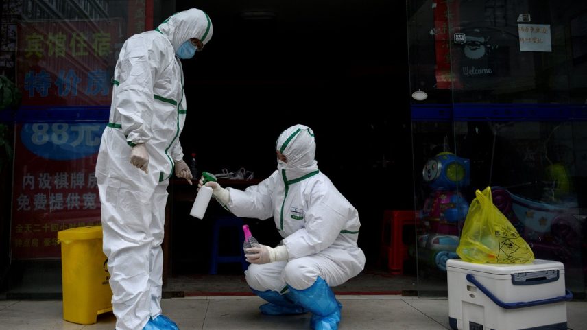 Médico em traje de proteção desinfeta colega em clínica de teste para Covid-19 em Wuhan, na China (Foto: Noel Celis / AFP)