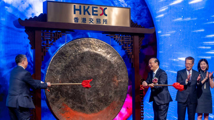 Robin Zeng, fundador e presidente da Contemporary Amperex Technology Co. Ltd. (CATL), à direita, toca um sino enquanto Paul Chan, secretário financeiro de Hong Kong, à esquerda, e Bonnie Chan, diretora executiva da Hong Kong Exchanges & Clearing Ltd. (HKEX), à direita, aplaudem durante a cerimônia de listagem da CATL na Bolsa de Valores de Hong Kong, em Hong Kong, China, na terça-feira, 20 de maio de 2025. (Foto: Paul Yeung | Bloomberg | Getty Images)