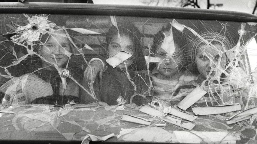 Quatro meninas olham de dentro de uma furgoneta com o vidro quebrado em Sarajevo. (Foto: Gervasio Sánchez)
