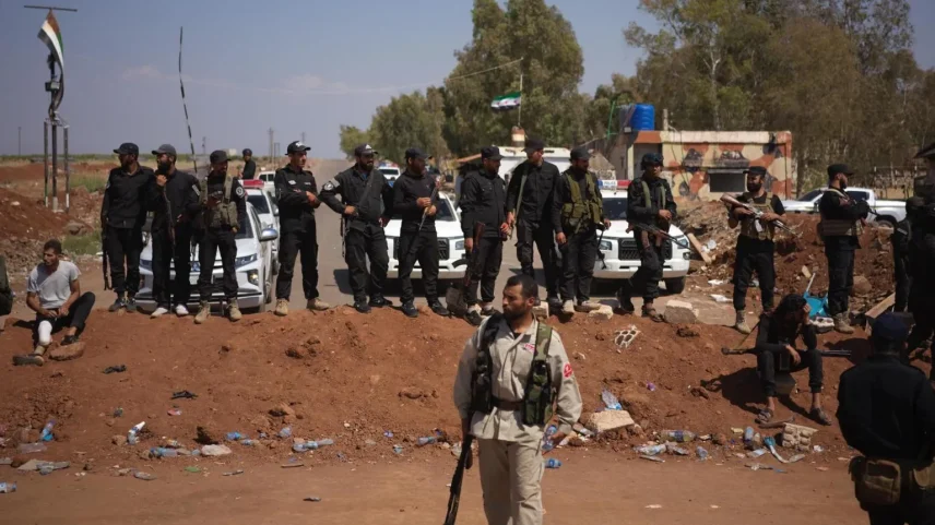 Dozens of government security personnel, all heavily armed, stand on an earthwork roadblock on the road to Suwedia, Syria. (Foto: Reprodução)
