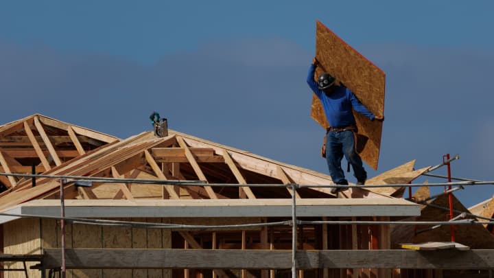 Um trabalhador da construção civil carrega uma chapa de OSB enquanto constrói um telhado em residências em Irvine, Califórnia, EUA, em 28 de março de 2025. (Foto: Mike Blake | Reuters)