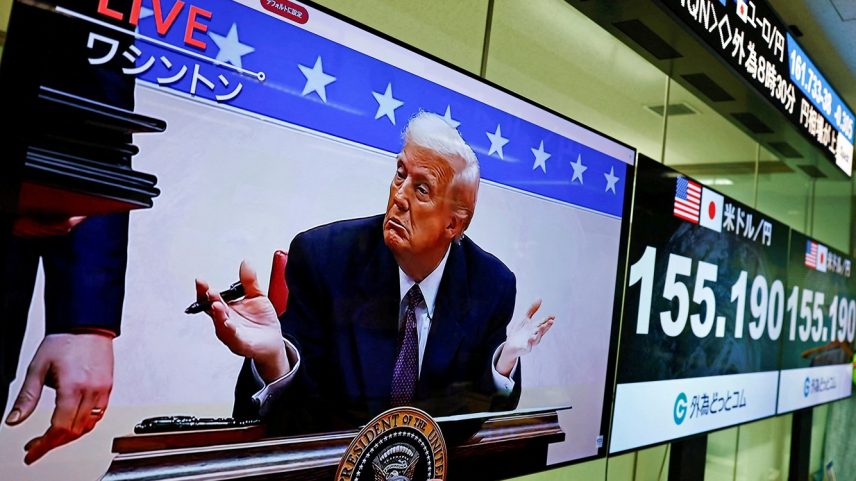 Uma tela transmitindo imagens ao vivo mostra o presidente dos EUA, Donald Trump, gesticulando enquanto assina ordens executivas ao lado de telas que exibem a taxa de câmbio atual do iene japonês em relação ao dólar americano na sala de operações da empresa de câmbio Gaitame.com, em Tóquio, Japão, 21 de janeiro de 2025. (Foto: REUTERS/Issei Kato/FOTO DE ARQUIVO)