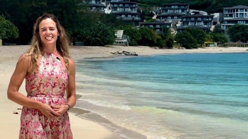 Nadia Dyson, dona da imobiliária Luxury Locations, sorri para a câmera de pé em uma praia de Antigua (Foto: Nadia Dyson)