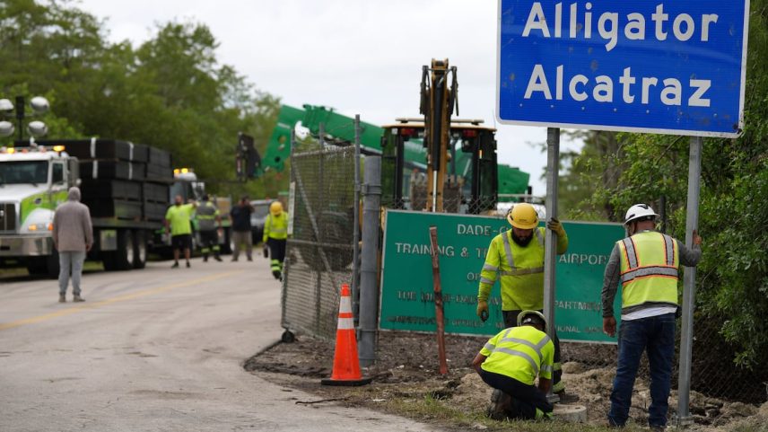 Operários instalam o cartel da prisão Alligator Alcatraz na via de entrada de suas instalações, em 3 de julho, na Flórida. (Foto: Associated Press/LaPresse)