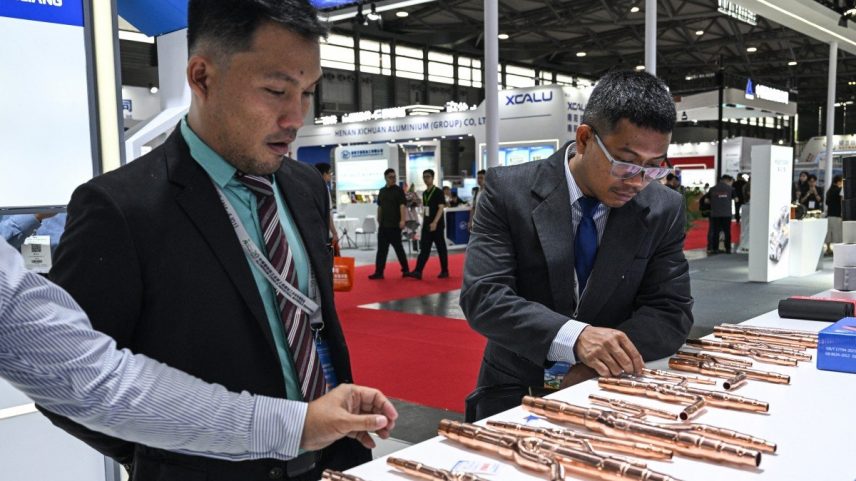 Visitantes verificam tubos de cobre em um estande durante a Feira Comercial Copper China 2025 (Foto: Hector RETAMAL / AFP)