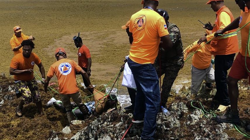 Defesa Civil recuperando o corpo de uma vítima de naufrágio na Praia de Juanillo, perto de Punta Cana (Foto: Handout / Defesa Civil da República Dominicana / AFP)