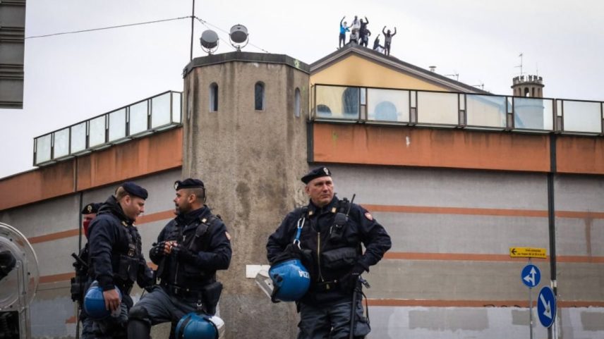Policiais italianos em frente à prisão de San Vittore, enquanto se vê atrás os detidos protestando no telhado da prisão em Milão (Itália), em 2020. (Foto: EFE)