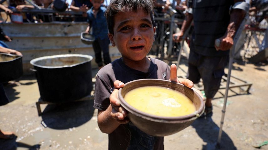 Um menino palestino segura um cuenco com comida recebida de um comedor de beneficência, em meio a uma crise de fome, na cidade de Gaza, este quinta-feira. (Foto: Dawoud Abu Alkas/REUTERS)