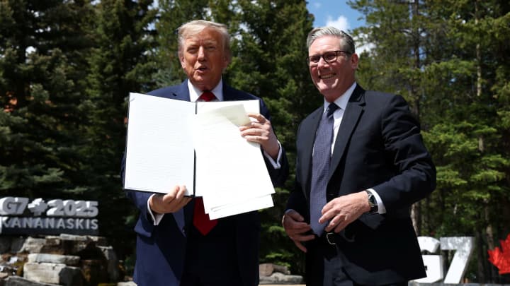 O presidente dos EUA, Donald Trump, e o primeiro-ministro britânico, Keir Starmer, reagem após pegarem o acordo comercial com os documentos do Reino Unido que Trump deixou cair enquanto falam com a mídia durante a cúpula do G7 em Kananaskis, Alberta, Canadá, em 16 de junho de 2025. (Foto: Kevin Lamarque | Reuters)