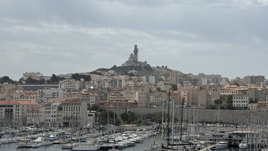 A cidade de Marselha, com o porto antigo, no primeiro plano, e a Basílica Notre Dame de la Garde, no fundo (Foto: Diogo Bercito/Folhapress)