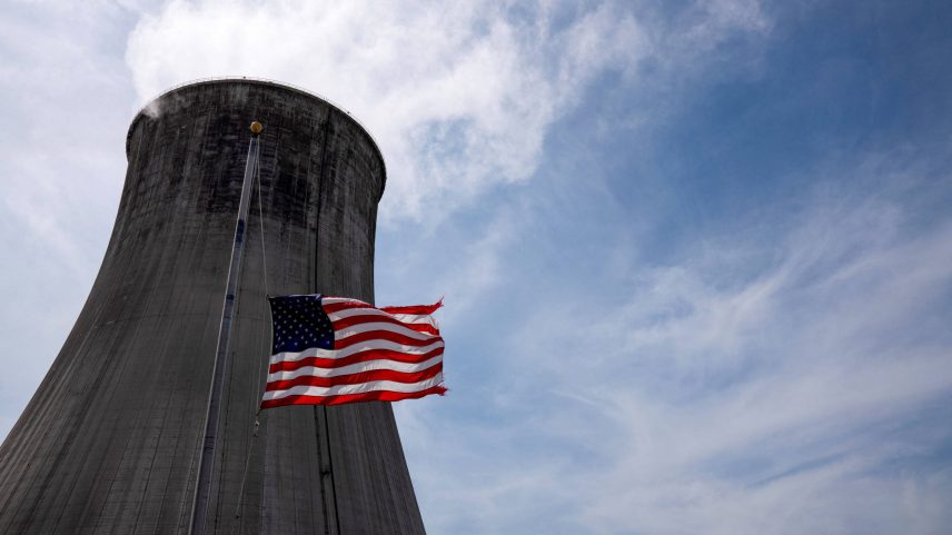 Bandeira americana tremula a meio mastro em frente à torre de resfriamento de uma usina termelétrica a carvão (Foto: Dane Rhys - 26.mar.21/Reuters)
