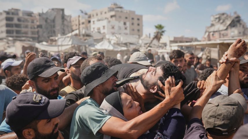 Um grupo de gazatíes carrega o corpo de uma pessoa que morreu quando buscava ajuda humanitária, este jueves em Gaza. (Foto: Jehad Alshrafi/AP)