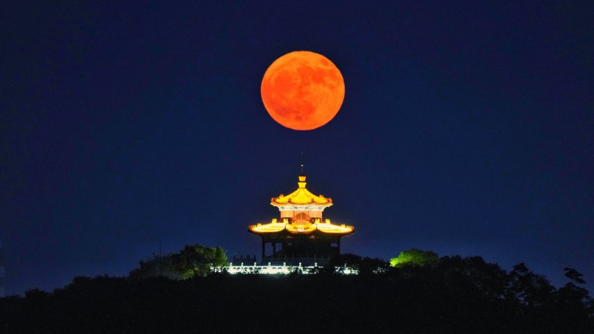 A lua cheia em formato de morango nasce sobre um campanário em 11 de junho de 2025 em Jilin, província de Jilin, na China (Foto: Sun Zhijun/VCG/Getty Images)
