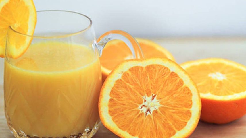 Copo com suco de laranja e laranjas cortadas ao meio ao lado (Foto: Getty Images)