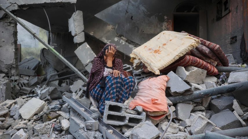 Mulher palestina chora sentada nos escombros de sua casa, destruída no ataque israelense contra o campo de refugiados de Nuseirat (Foto: Eyad Baba/AFP)
