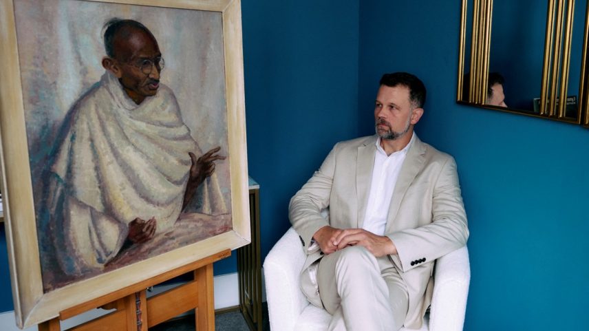 Caspar Leighton, sobrinho-neto da artista anglo-americana Clare Leighton, posa ao lado do retrato de Ghandi feito por sua tia-avó (Foto: BENJAMIN CREMEL / AFP)