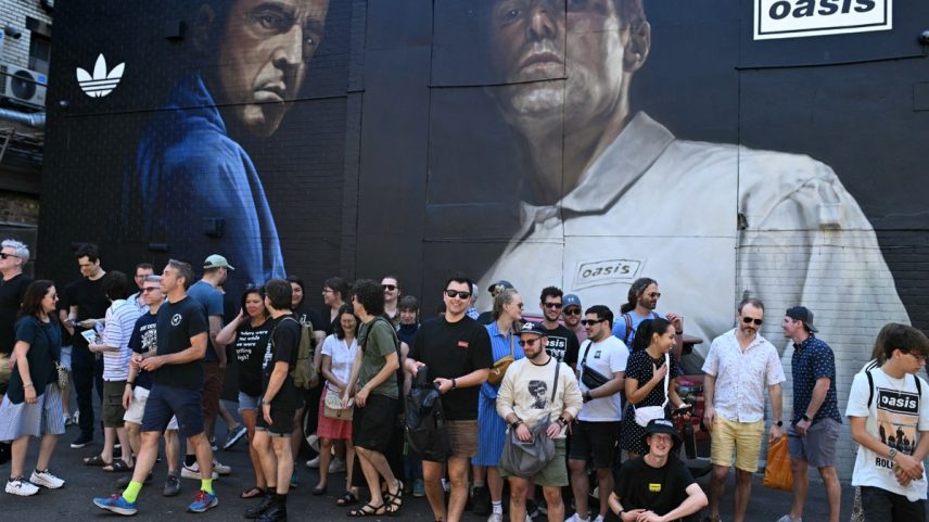 Fãs se reúnem em frente a mural dos irmãos Noel e Liam Gallagher, do Oasis, em Manchester (Foto: OLI SCARFF / AFP)