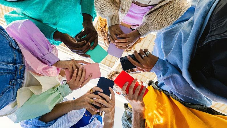 Um grupo de jovens segurando telefones móveis. (Foto: Xavier Lorenzo/Getty Images)