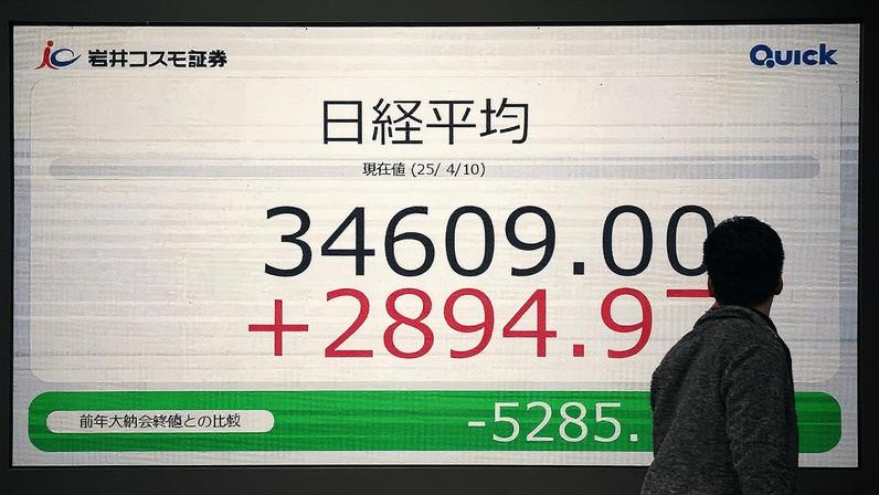 Um homem observa um painel eletrônico que mostra os números do Índice Nikkei na Bolsa de Valores de Tóquio (Foto: Kazuhiro Nogi/AFP)