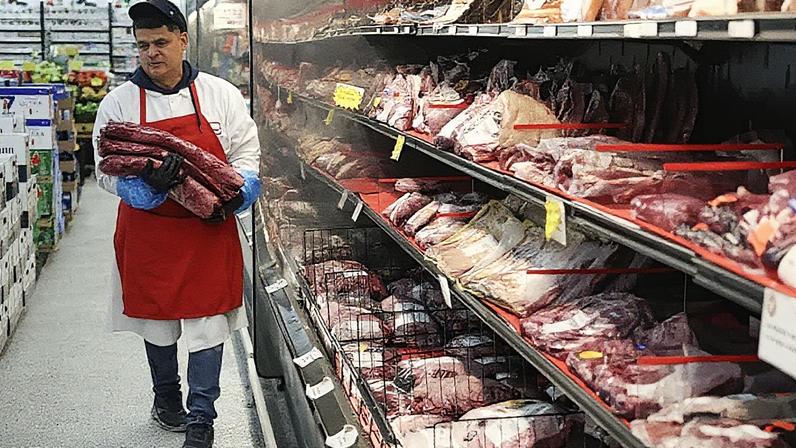 Marlo Ramirez carrega pedaços de carne para serem preparados para um cliente em um supermercado em 22 de julho de 2025 em Miami, Flórida. (Foto: Joe Raedle | Getty Images)