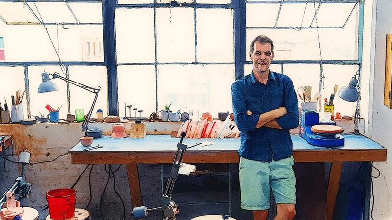 Artista Jono Pandolfi em seu ateliê, cercado por peças de cerâmica e ferramentas de trabalho (Foto: Reprodução)
