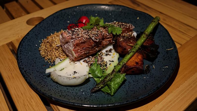 Atum grelhado na brasa, acompanhado por batata-doce assada, acelga japonesa, tomates-cereja, farofa de alho e redução à base de vinho do Porto e balsâmico