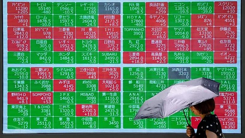 Uma mulher passa por um painel eletrônico mostrando o índice Nikkei 225 na Bolsa de Valores de Tóquio, em uma rua no centro de Tóquio, em 22 de julho de 2025. (Foto: Kazuhiro Nogi | Afp | Getty Images)